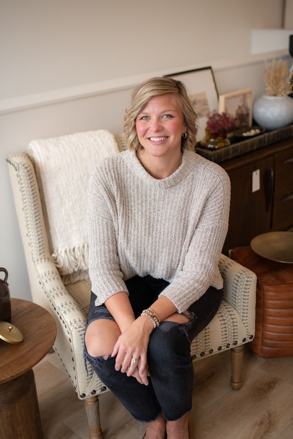 Person in cozy sweater sitting comfortably in cream-colored armchair.