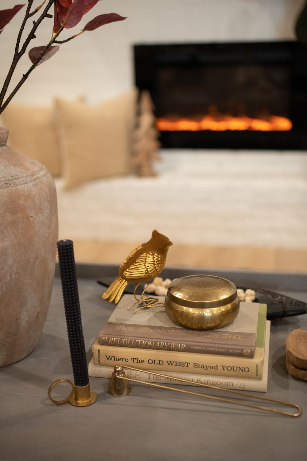 Styled vignette with vintage books, brass bird figurine, and decorative objects on table surface.