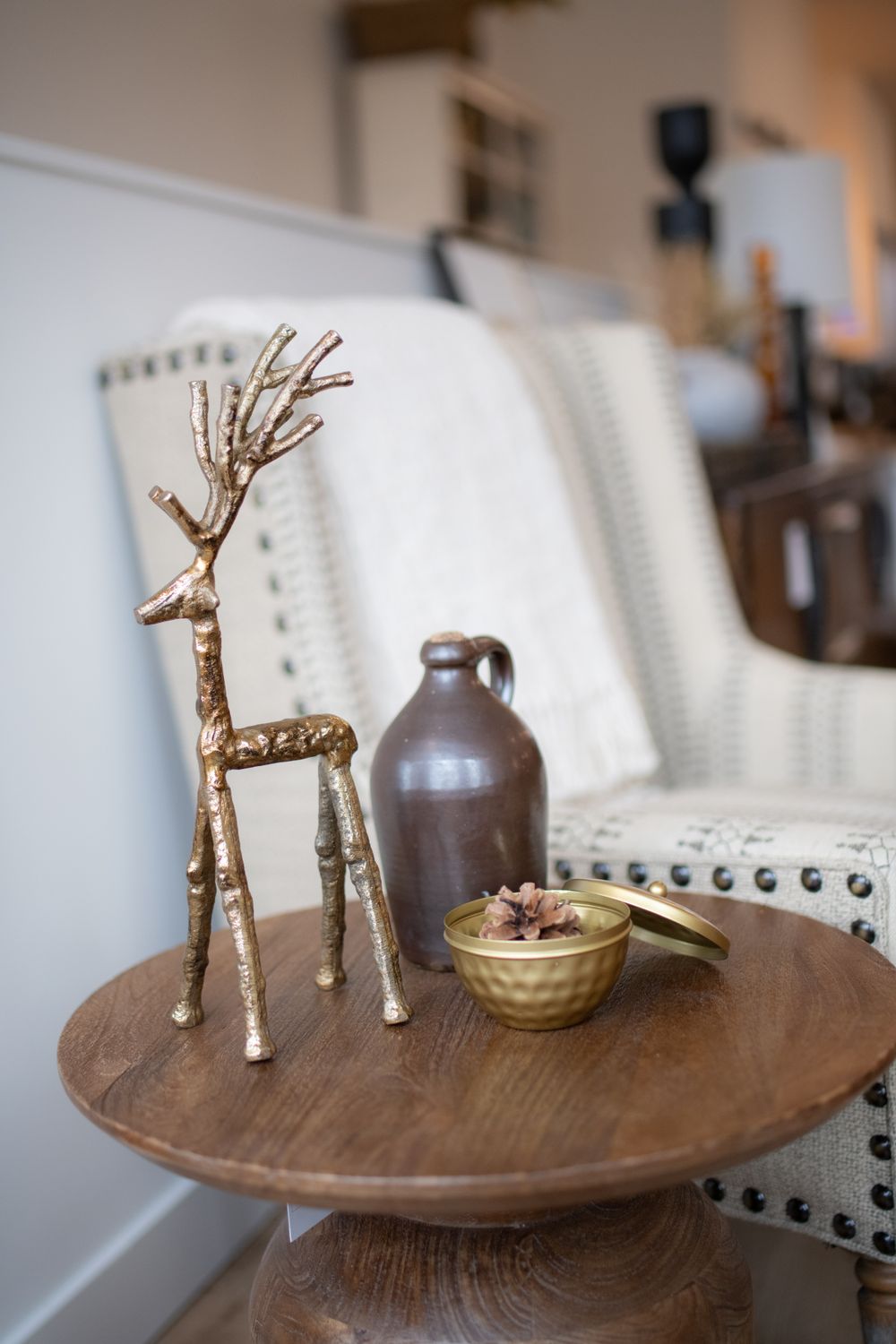 Decorative gold reindeer figurines displayed on wooden side tables with white upholstered seating.