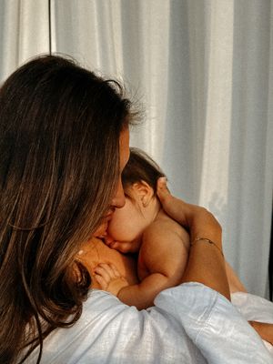 A brunette woman allows her baby to snuggle into her neck