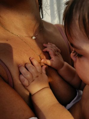 A baby playing with her mothers necklace