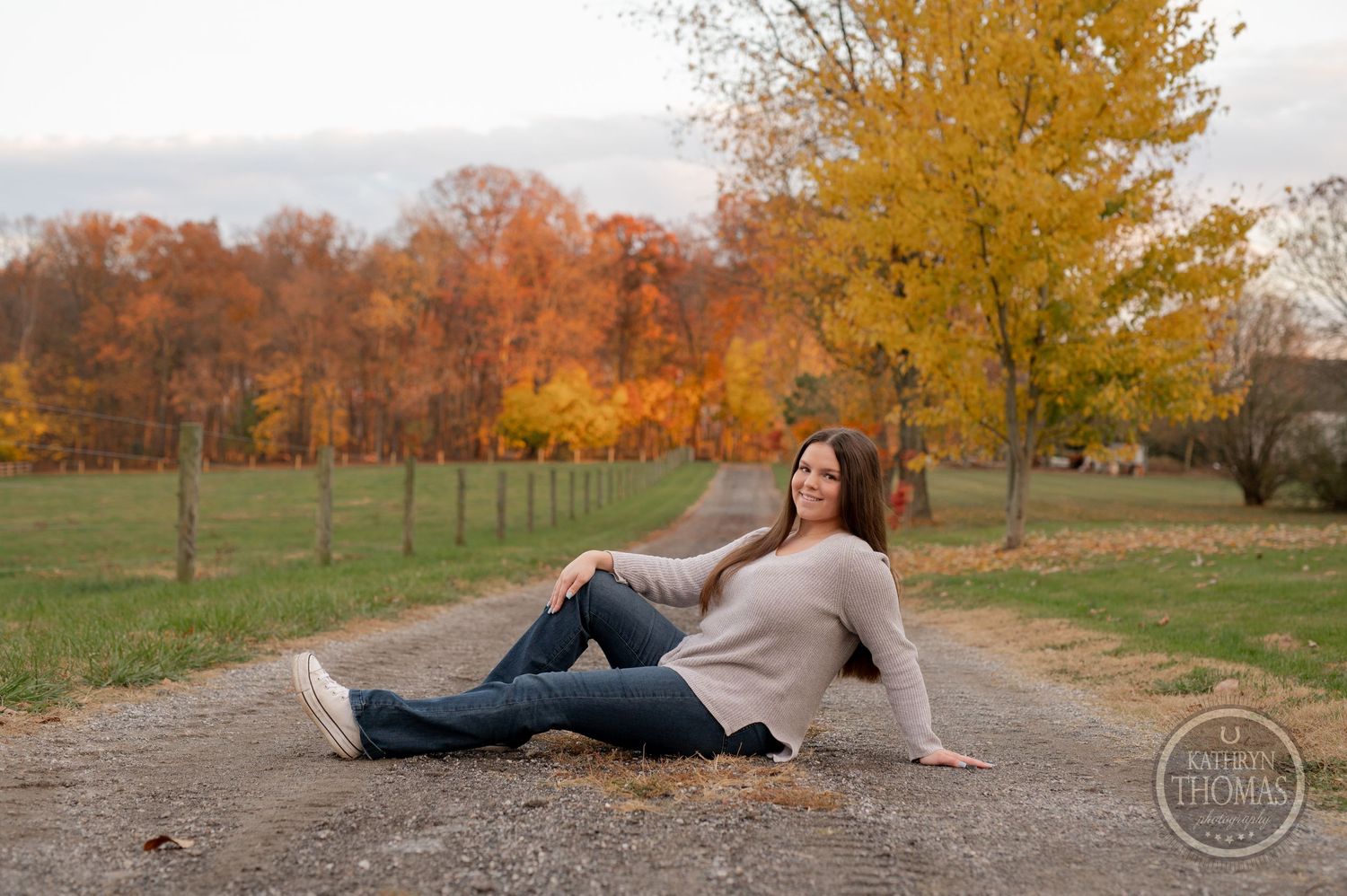 Relaxed pose on country path surrounded by fall colors and fencing.