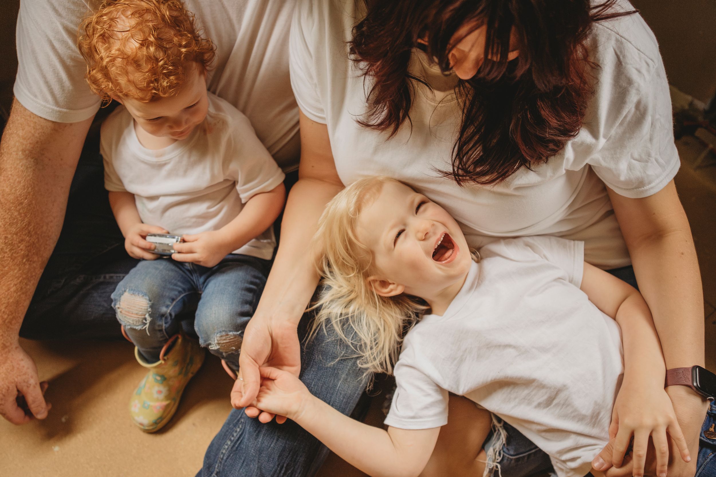 Family relaxing together on wooden floor during home renovation project.