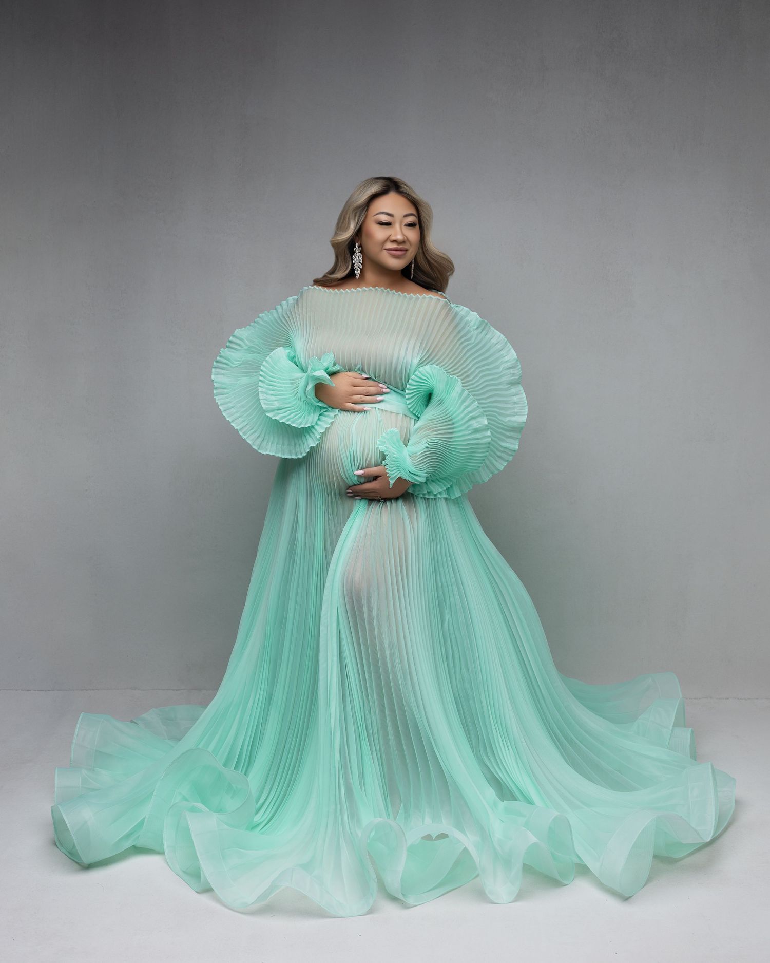 A flowing mint green tulle gown is shown from multiple angles against a gray backdrop.
