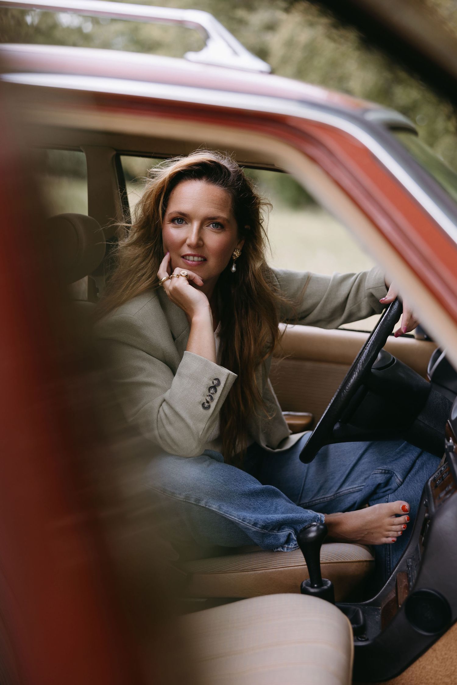 Vintage style photo of person in classic car wearing blazer and jeans.