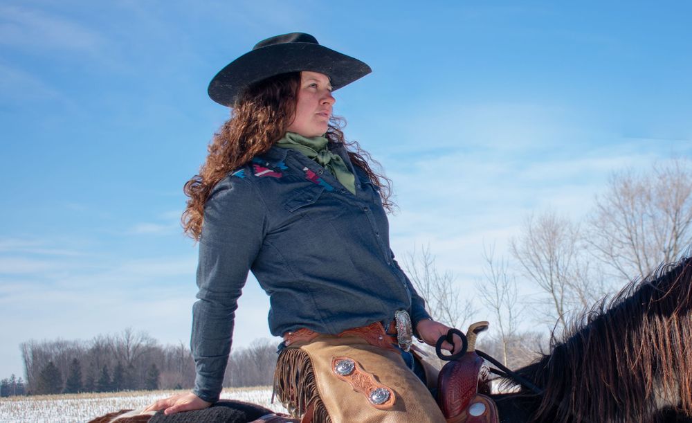 Western Cowgirl on horseback looking off into distance in a Wisconsin winter scene
