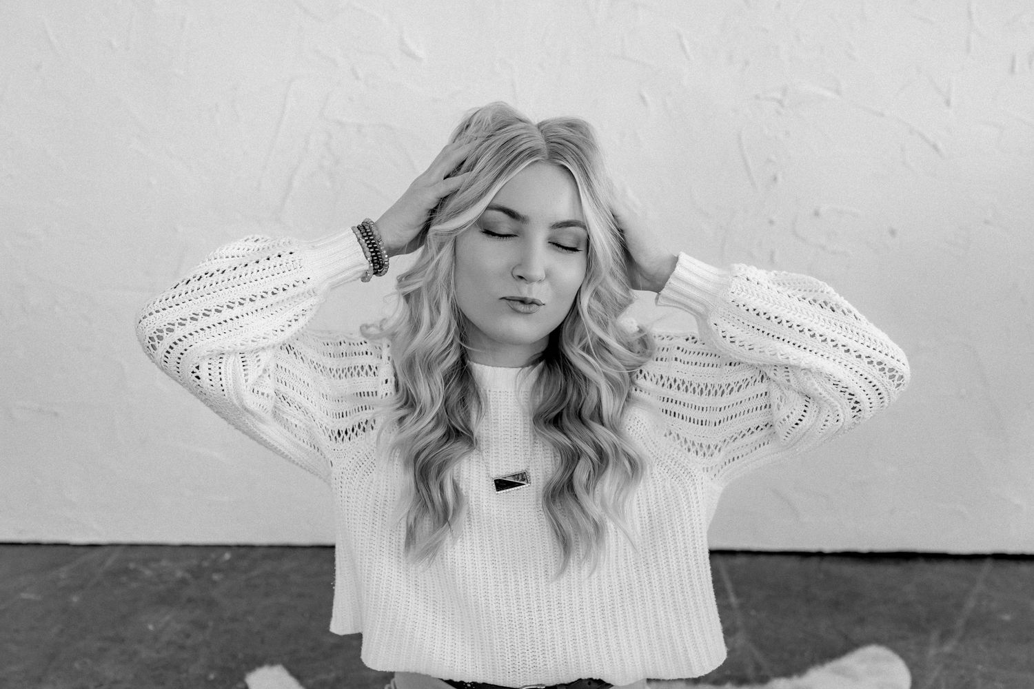 Woman in white sweater posing dramatically in black and white portrait series.