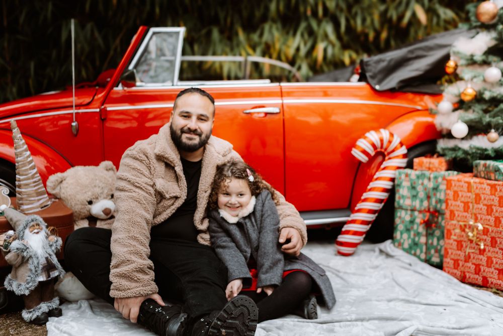 Mini-session photo de Noël 2024 avec une coccinelle VW rouge décorée pour les fêtes, créant une ambiance festive et chaleureuse.