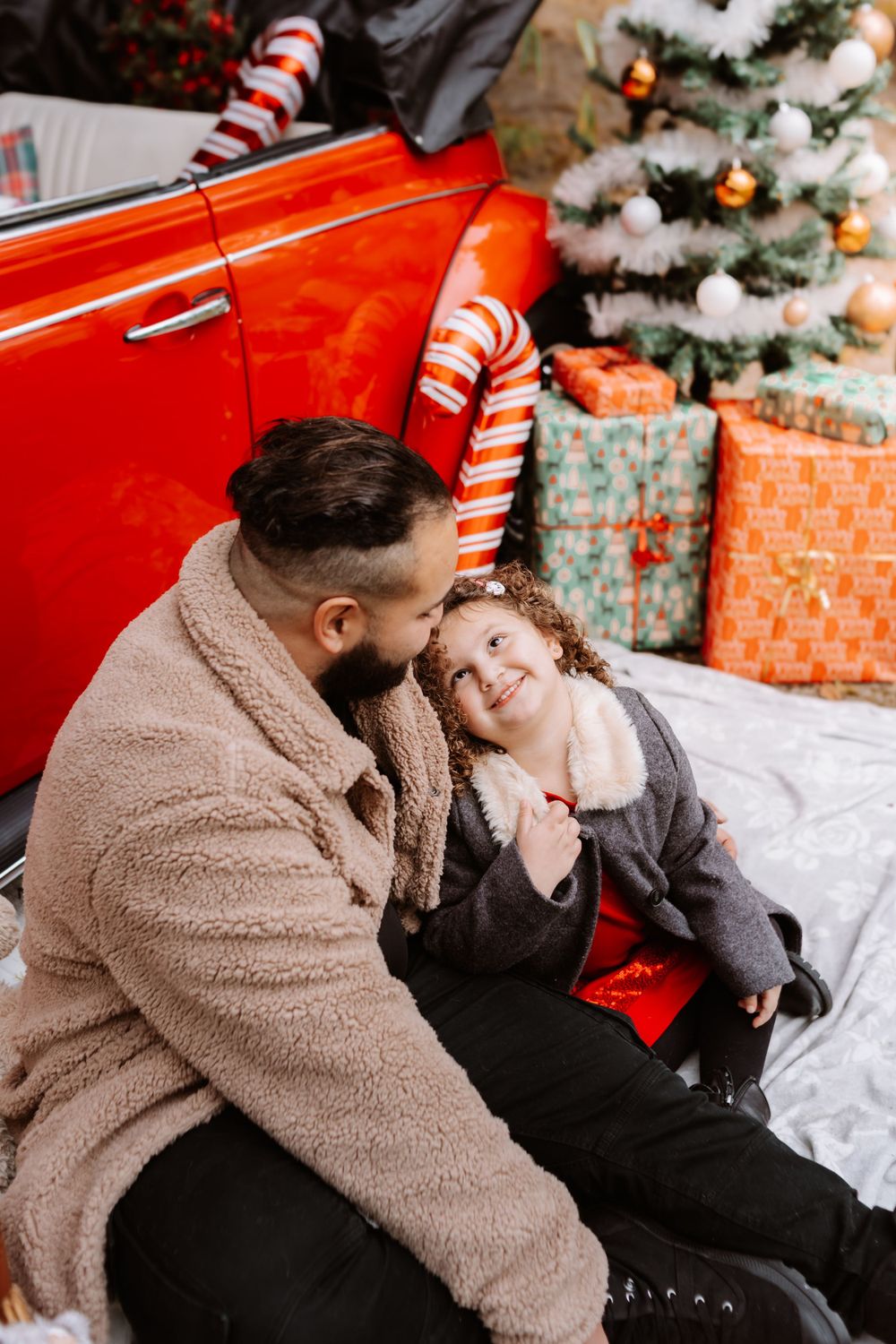 Mini-session photo de Noël 2024 avec une coccinelle VW rouge décorée pour les fêtes, créant une ambiance festive et chaleureuse.