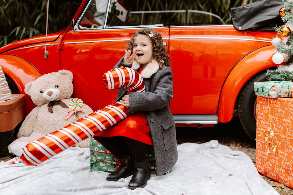 Mini-session photo de Noël 2024 avec une coccinelle VW rouge décorée pour les fêtes, créant une ambiance festive et chaleureuse.
