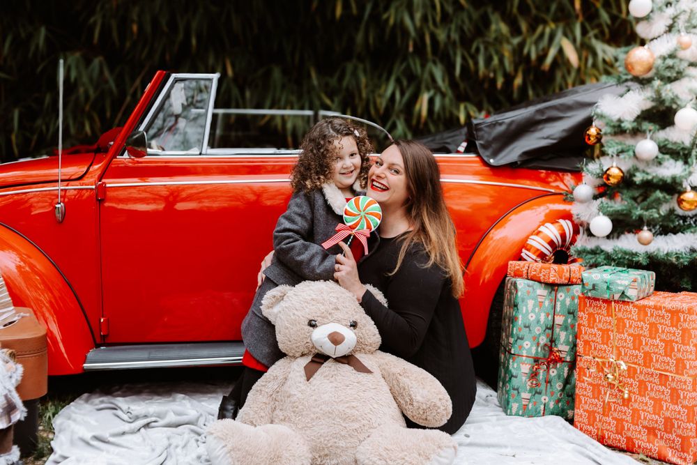 Mini-session photo de Noël 2024 avec une coccinelle VW rouge décorée pour les fêtes, créant une ambiance festive et chaleureuse.