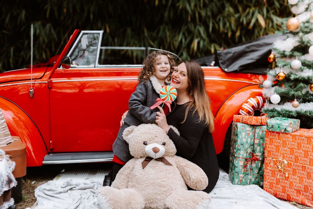 Mini-session photo de Noël 2024 avec une coccinelle VW rouge décorée pour les fêtes, créant une ambiance festive et chaleureuse.