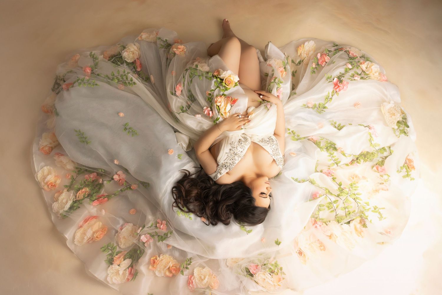 Overhead view of maternity portrait with floral dress spread in circular pattern.