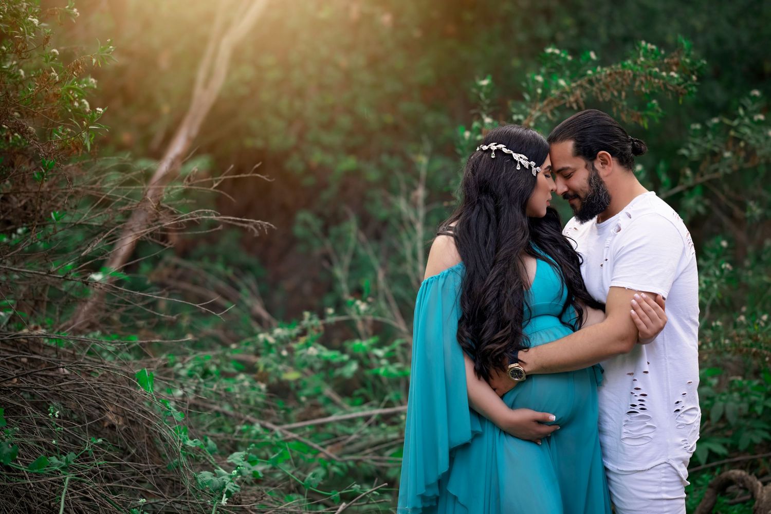 A romantic outdoor maternity shoot with flowing turquoise dress in natural setting.