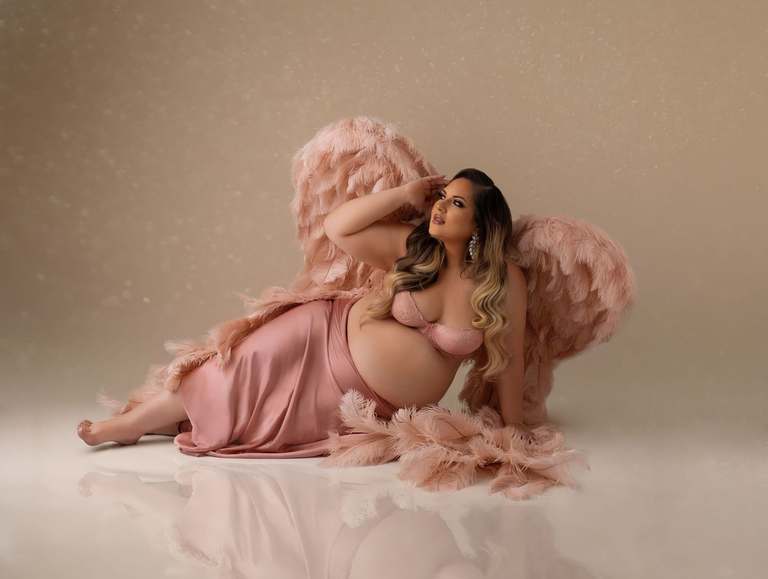 Dreamy maternity portrait with soft pink tones and fluffy textures creating a romantic atmosphere.