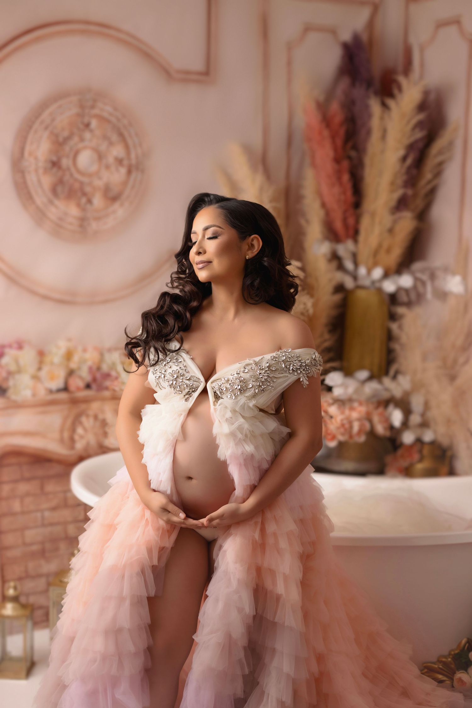 Romantic maternity portrait in off-shoulder pink tulle gown with pampas grass decor.