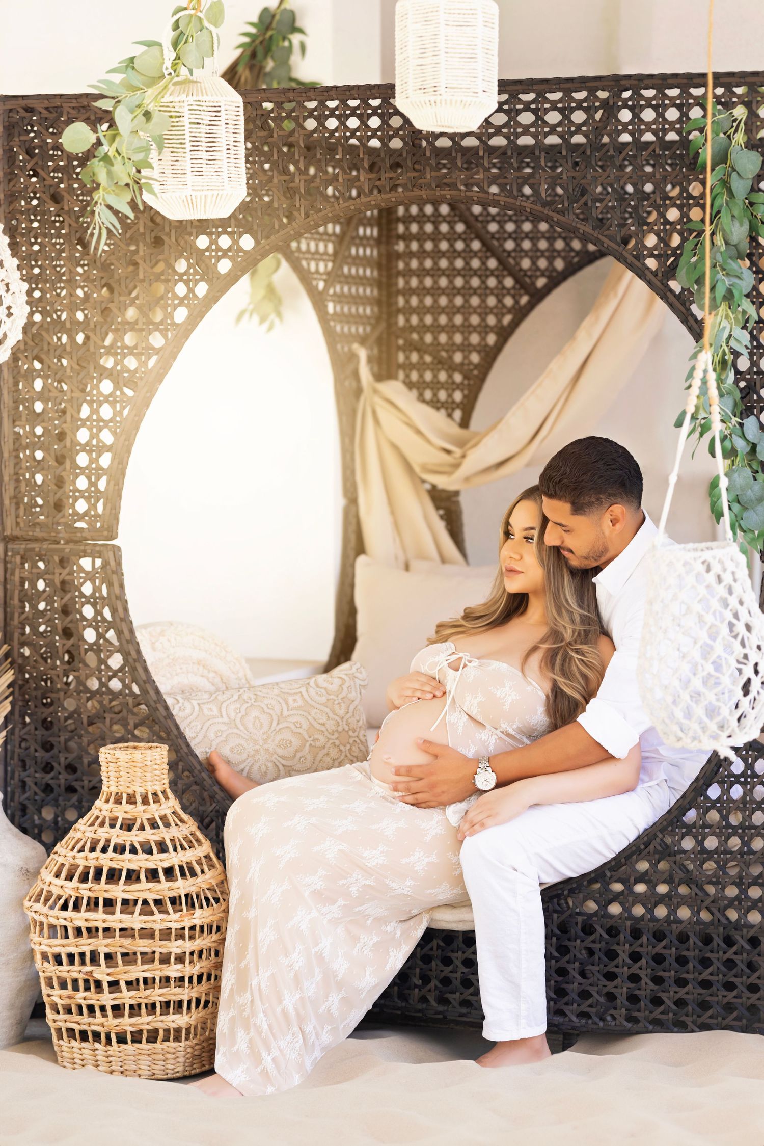 An intimate maternity moment captured in an outdoor cabana with woven accents.