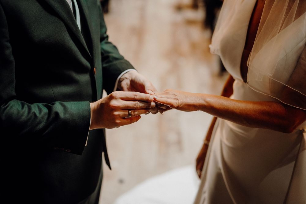 A close-up shot of hands exchanging wedding rings during an intimate ceremony.