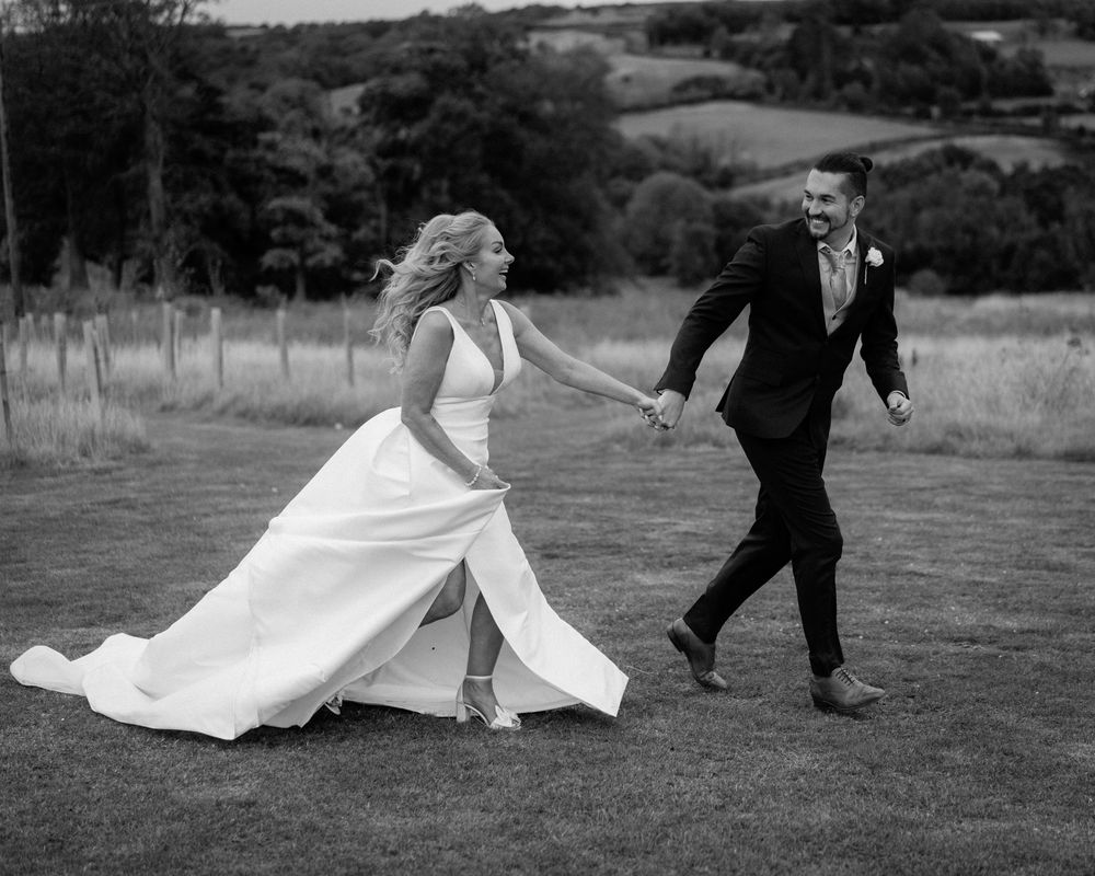 A black and white sequence of images showing a flowing wedding dress and formal attire in motion across a rural landscape.