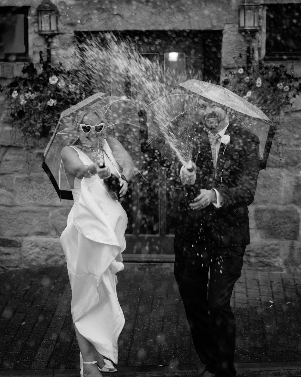 A black and white wedding photo sequence showing a couple playfully throwing confetti and laughing together outside.