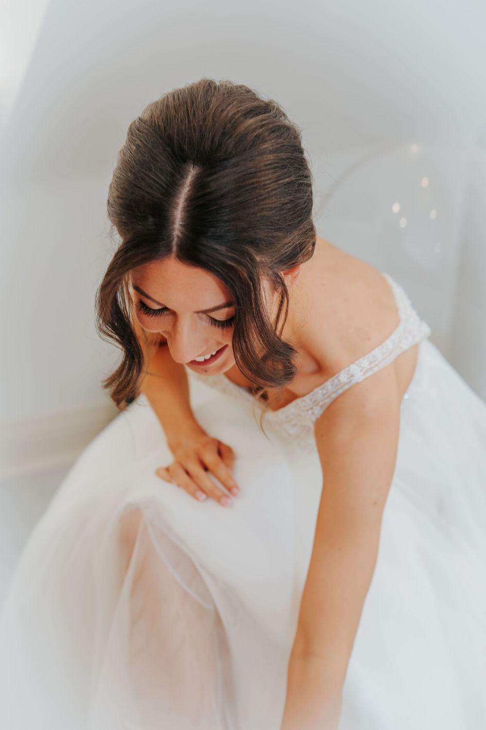 Close up view of a white wedding dress with delicate lace details in natural lighting.