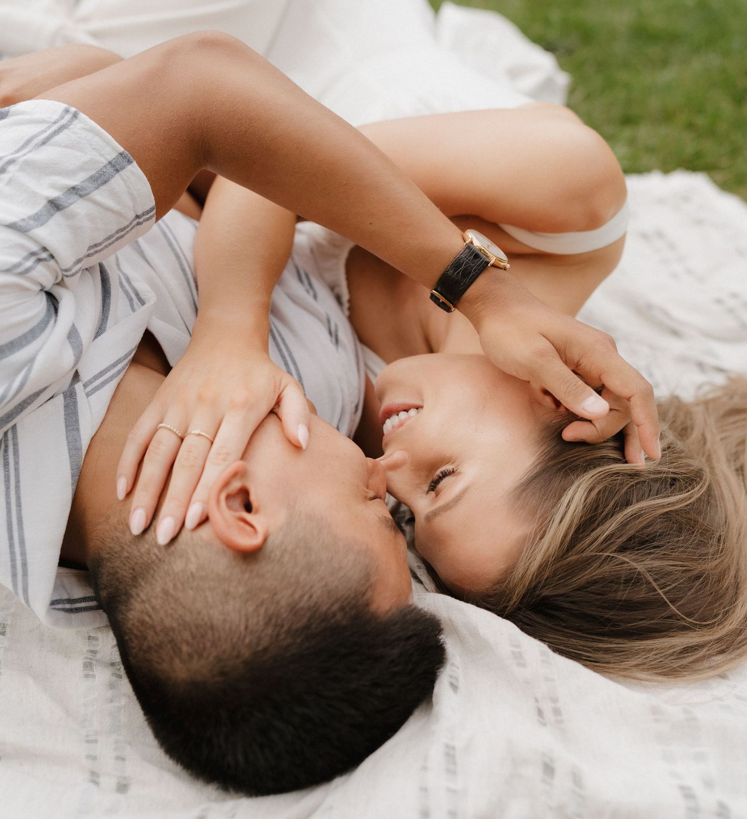 an engaged couple intimately embraced on a summer day at the park.
