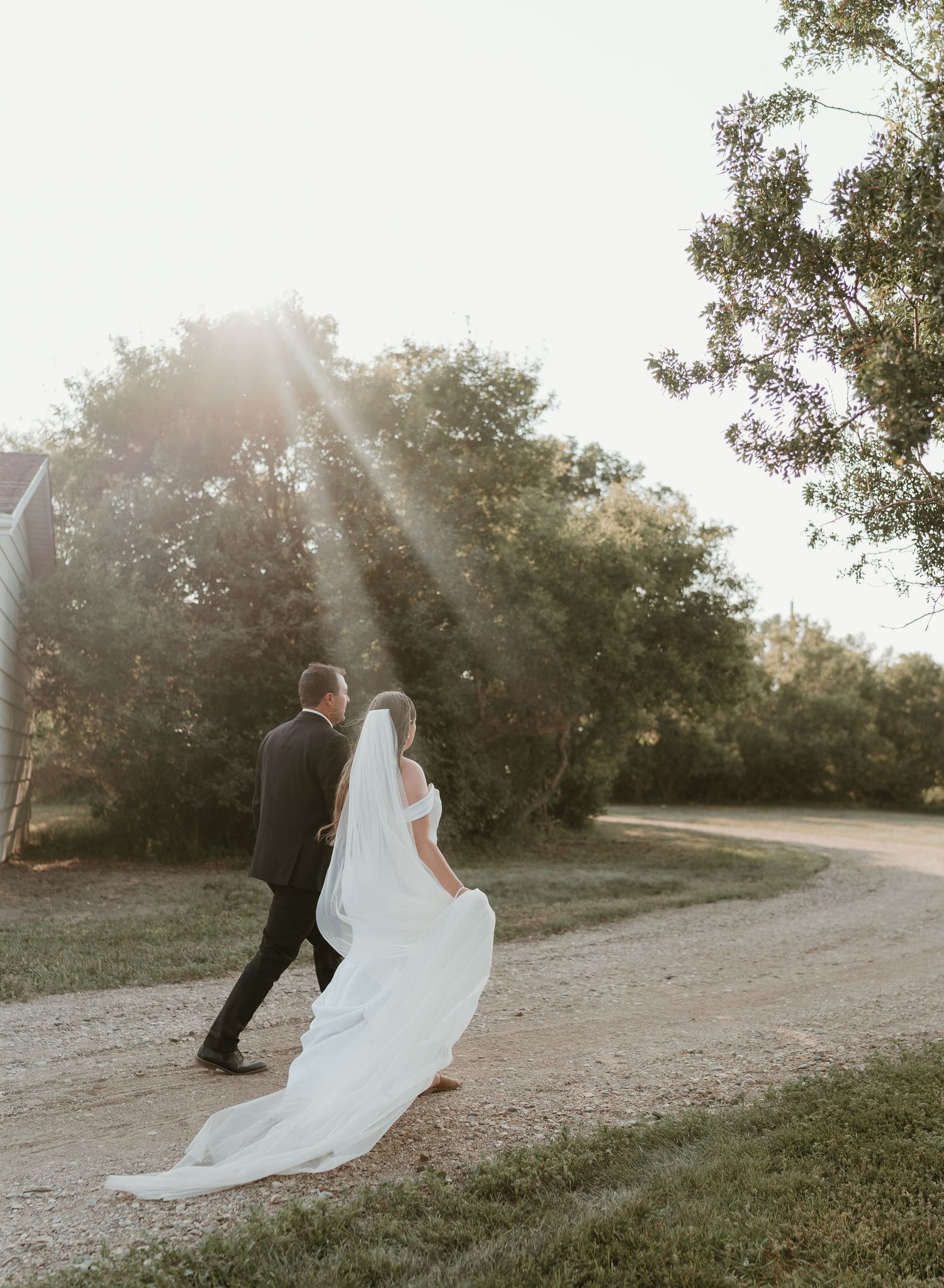 A bride and groom sharing a romantic walk together while the sun shines through the trees.