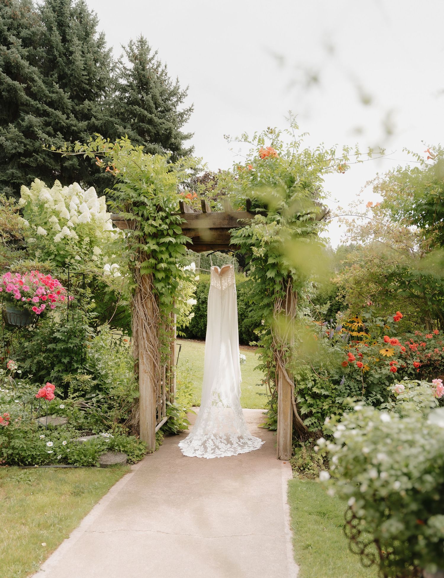 wedding dress hanging in soft natural light during Kelowna, BC wedding, surrounded by beautiful flowers