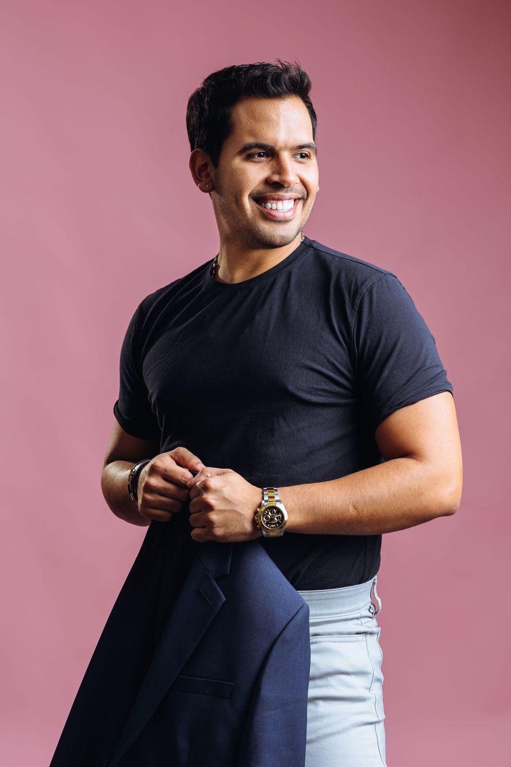 Stylish casual portrait showing navy blazer and black t-shirt combination against pink wall.