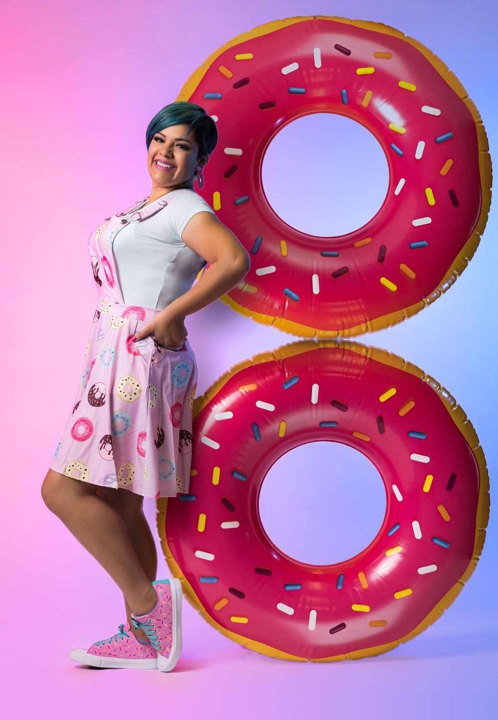 Fun portrait with giant donut pool floats against colorful gradient background.