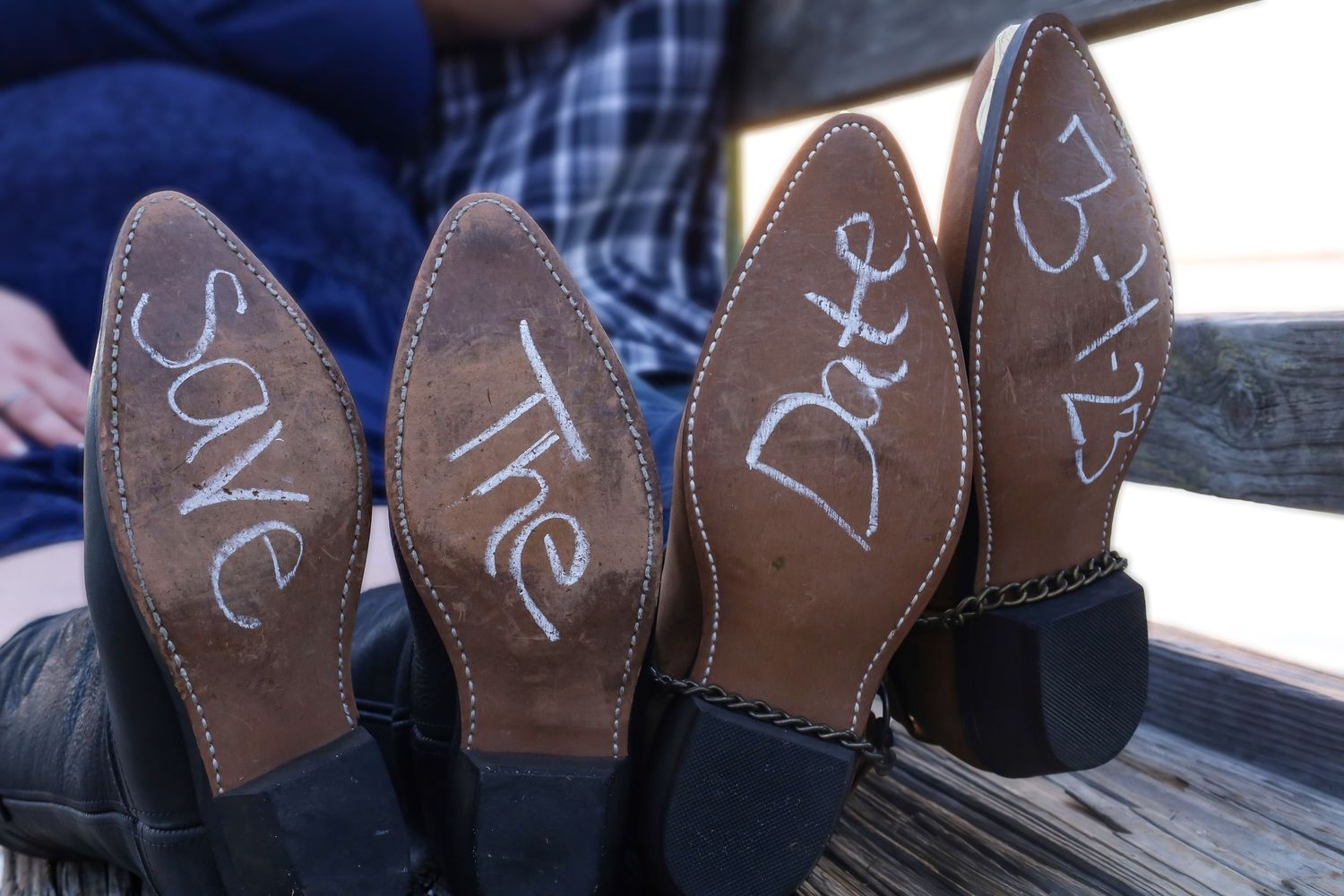 Cowboy boots with Save The Date written on soles, creative wedding announcement photo.