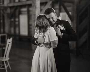 Bride and groom share an emotional first dance embrace in a black and white wedding photo.