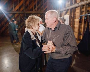 Elderly couple dancing together in a rustic barn venue at a wedding reception.