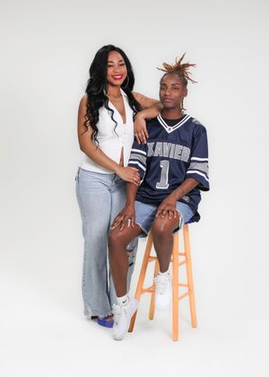 Two people posing for a portrait, one wearing a Xavier jersey number 1, against a white background.