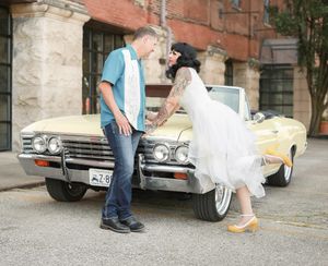 Vintage yellow Chevrolet Impala convertible parked on street with couple in rockabilly retro style outfits.