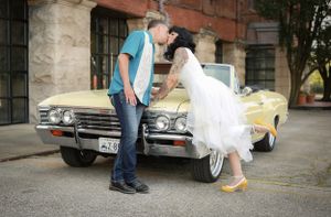 A vintage yellow Chevrolet Impala convertible serves as backdrop for a retro-styled photo with two figures in casual and formal attire.