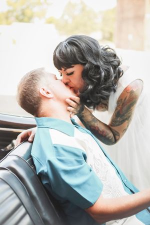 A passionate moment captured between newlyweds with vintage styling in a classic car.