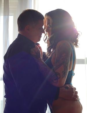 A couple shares an intimate moment in silhouette by a bright window.