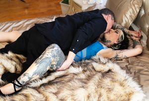 Someone lies asleep on a furry rug wearing blue and black clothing while resting on a cozy bed.