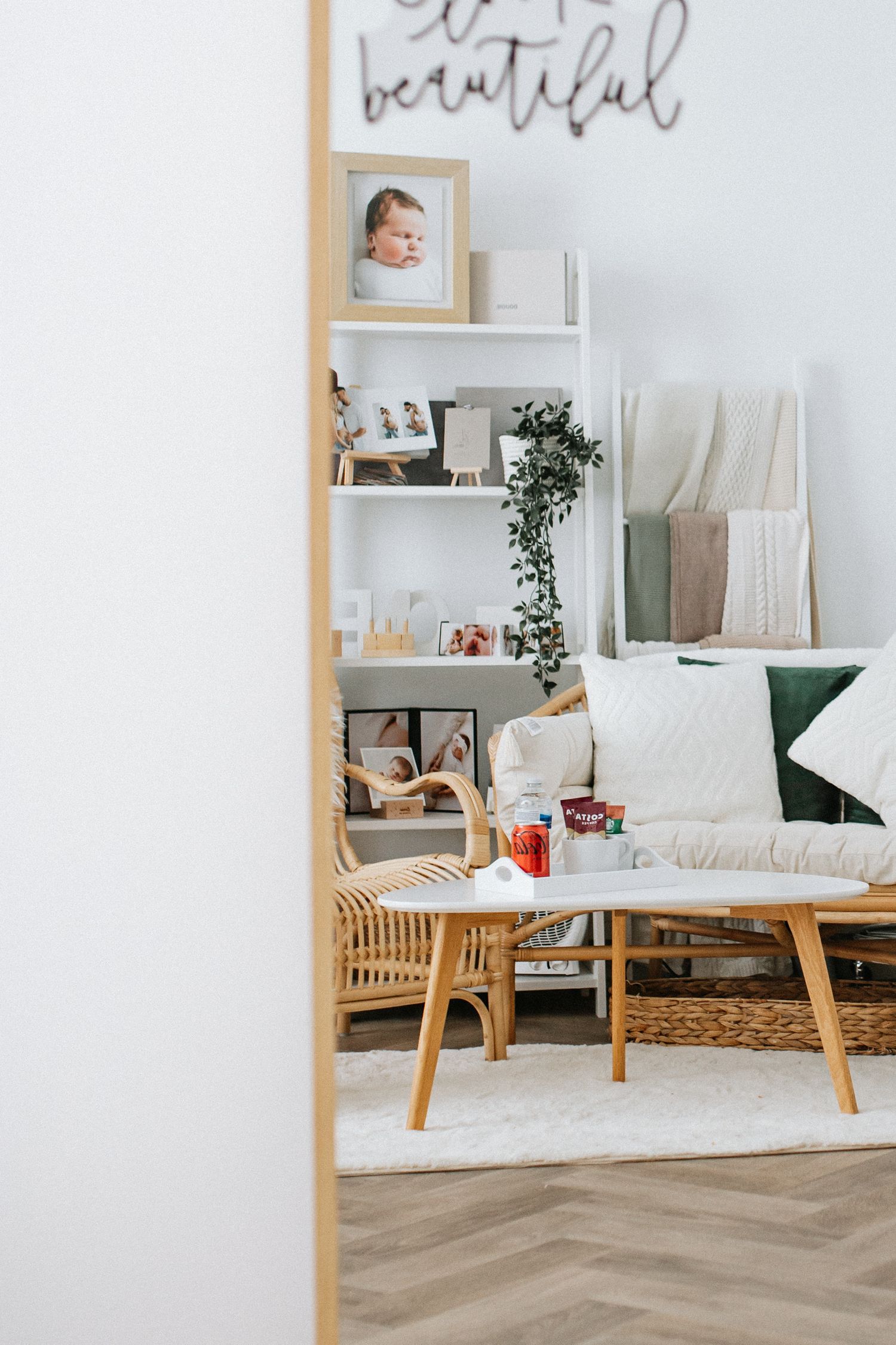Cozy modern living room corner with white couch, wooden furniture and decorative wall shelving.