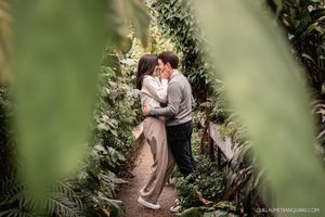 Romantic moment captured in a lush garden setting with greenery in the foreground.