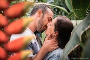 Romantic couple shares intimate moments among orange flowers and greenery.