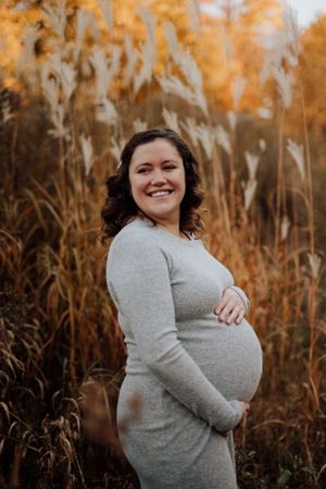 Future maman rayonnante posant dans un champ à l’automne au Québec, lors d’une séance maternité naturelle.