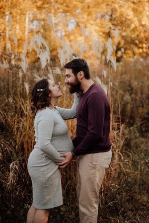 Photo de grossesse en automne : couple attend un enfant dans un champ doré au Québec.