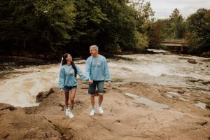 Séance couple en nature sur les rochers au bord d’une rivière, ambiance décontractée.