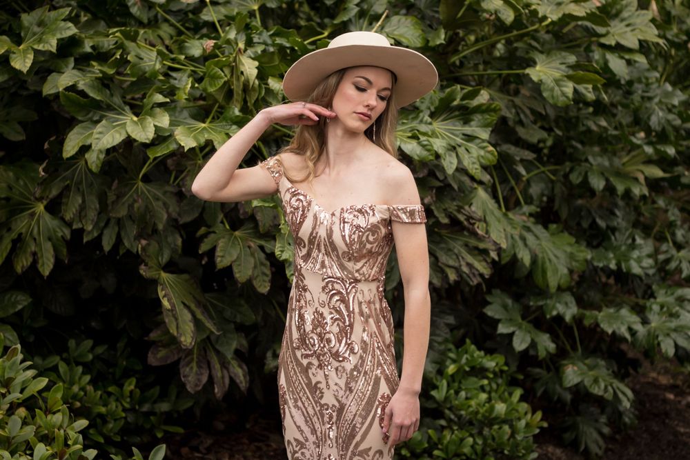 Romantic garden portrait featuring intricate beaded gown and wide-brimmed hat.