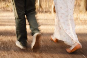Motion-blurred detail of feet walking on a sunlit path.