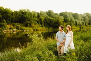 A couple enjoying a peaceful moment by a serene lake surrounded by summer foliage.