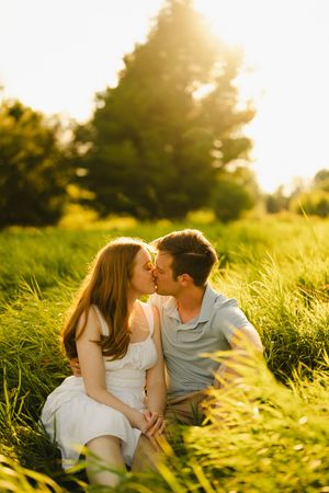 A tender moment shared between a couple in a sunlit meadow.