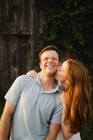 A joyful couple sharing laughter against a dark wooden background.